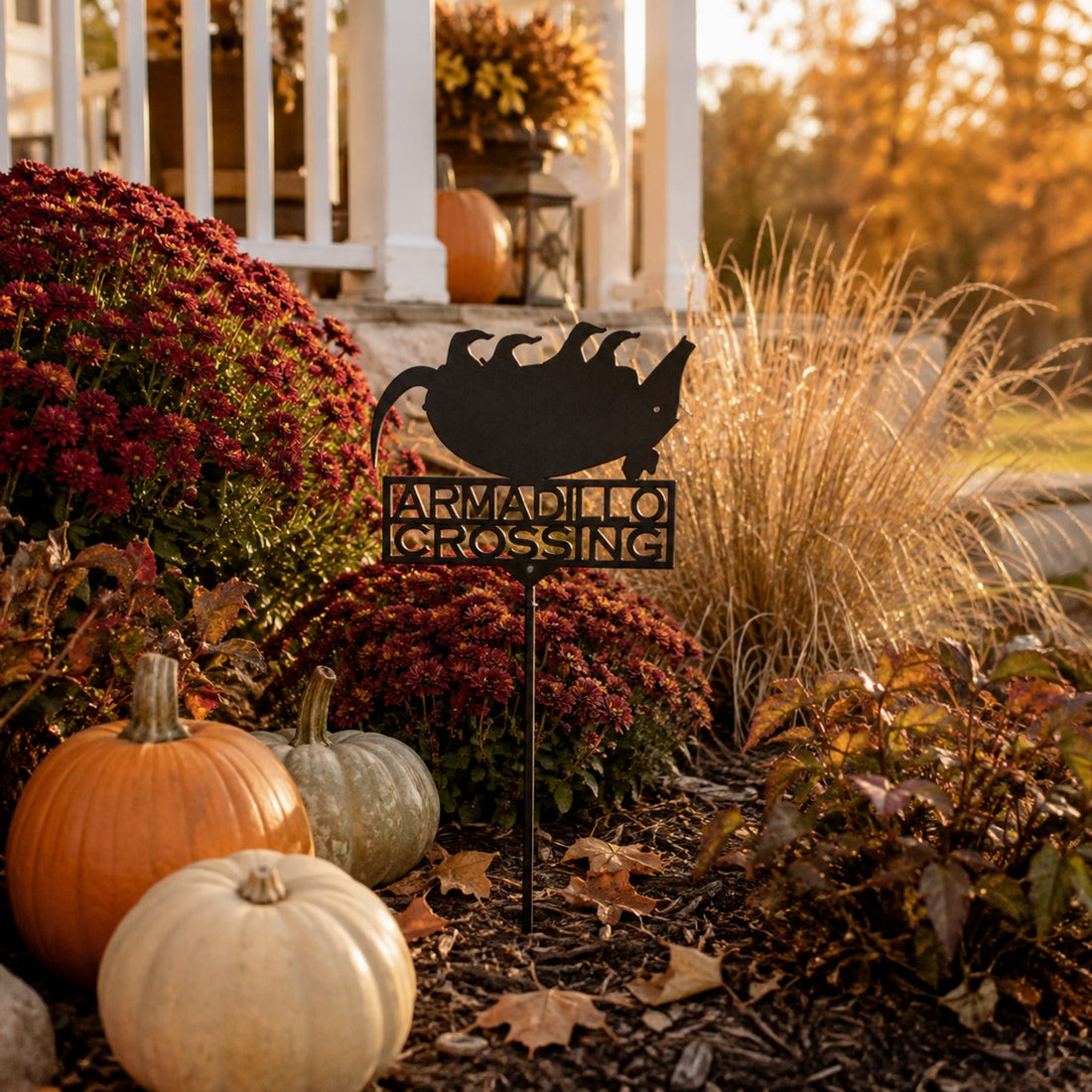Matte Black Dead Armadillo Crossing metal garden stake displayed with pumpkins and fall flowers