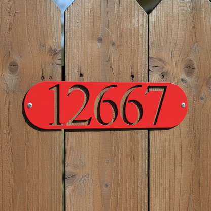 Close-up of red oval address plaque on fence
